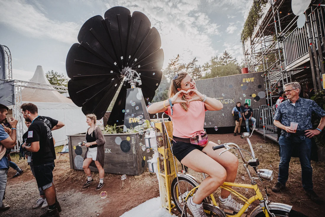 Festivalbesucherin erzeugt auf dem EWE Kraftwerk per Fahrrad Strom und erlebt die interaktive Installation auf dem Tante Mia Tanzt Festival.