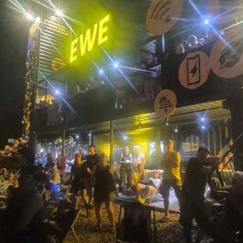 Der beleuchtete EWE Power Tower mit zahlreichen Festivalbesuchern am Abend.