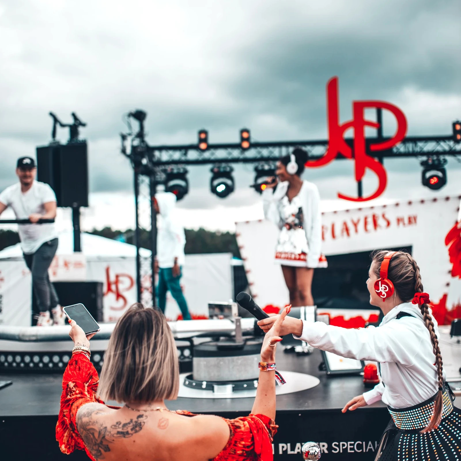 Mehrere junge Frauen der JSP-Festival-Tour feuern einen Mann an, der auf einem begehbaren XXL-Plattenspieler l&auml;uft.