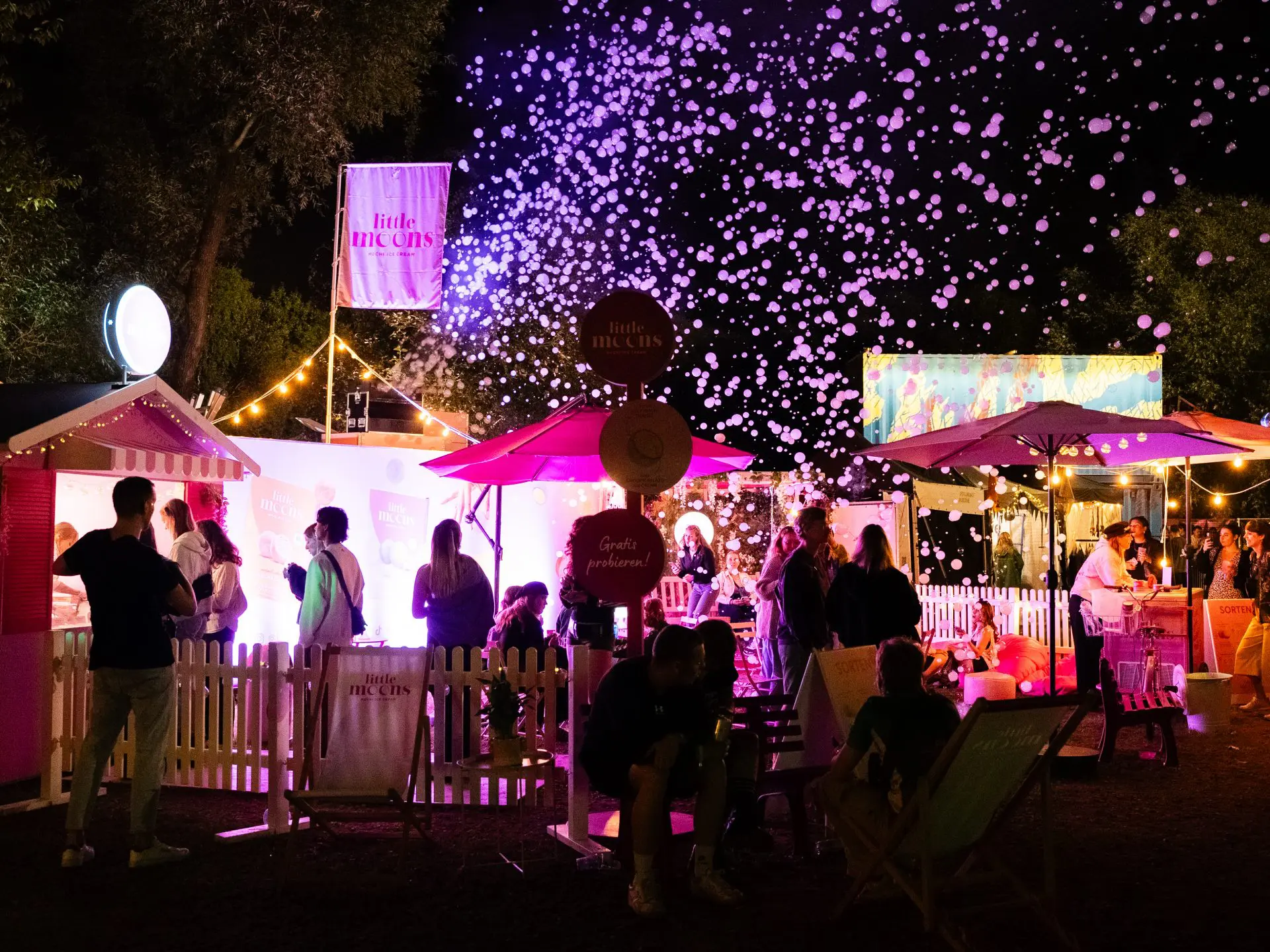 Der beleuchtete Little-Moons-Festival-Garden mit Seifenblasen und Festivalbesuchern am Abend.