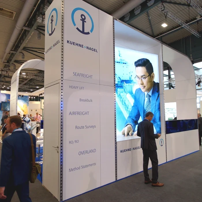 Übereckperspektive auf den Kühne und Nagel Messestand, mit großem Leuchtmotiv und abgerundeten Konstruktions-Elementen.